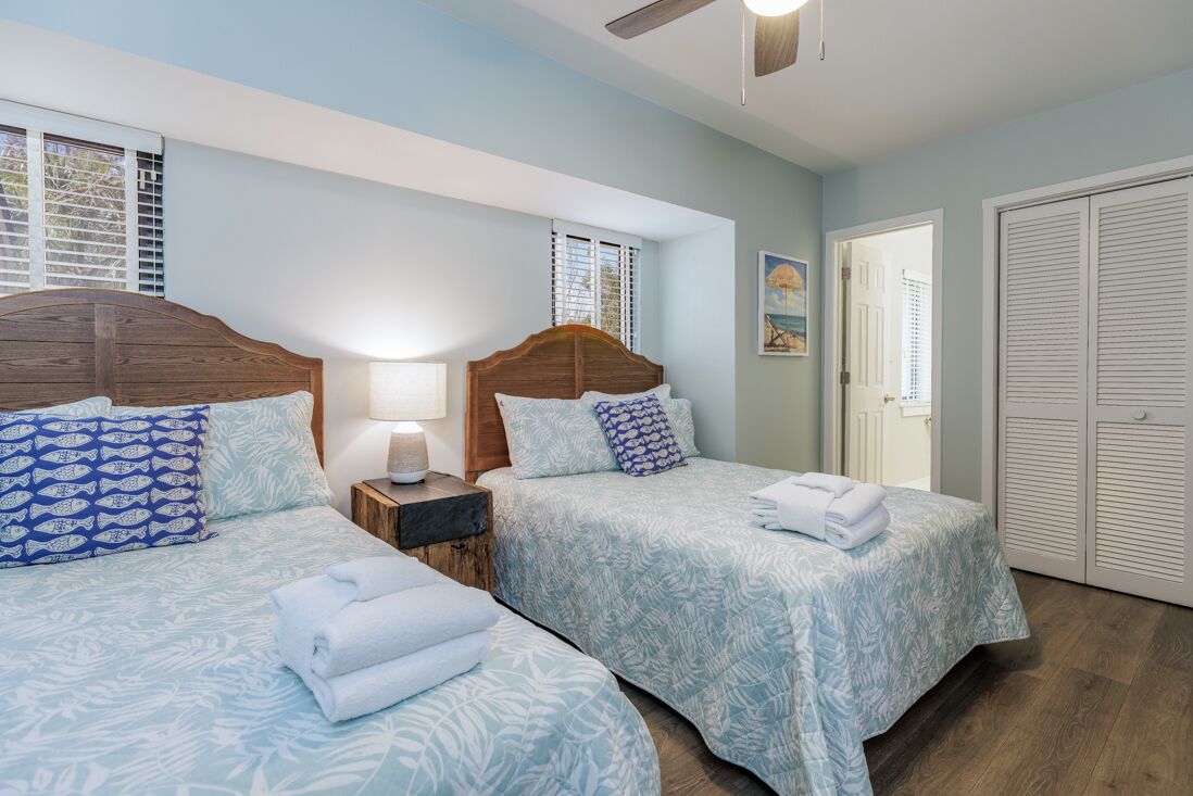 A bedroom with two beds, each with a wooden headboard, a nightstand, and a lamp.