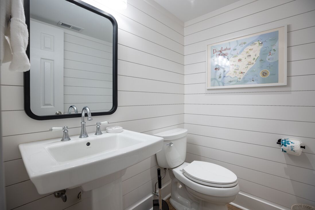 A bathroom with a white sink, a toilet, and a framed map on the wall.
