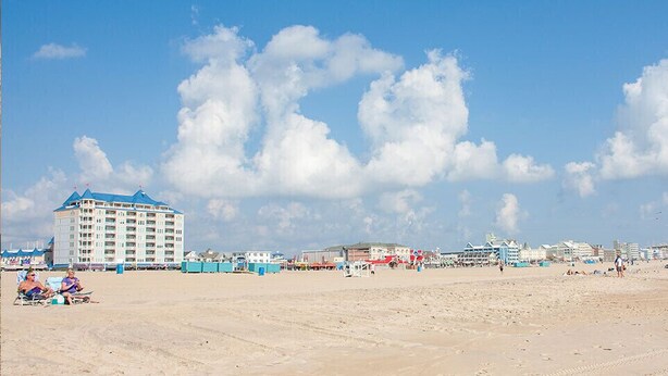 Ein Strand mit einem großen Hotel und mehreren kleineren Gebäuden im Hintergrund.