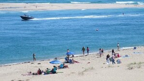 A beach with people sunbathing and swimming, a boat in the water, and a clear sky. - Historic Sea Captain's Home in Downtown Chatham (Chatham)