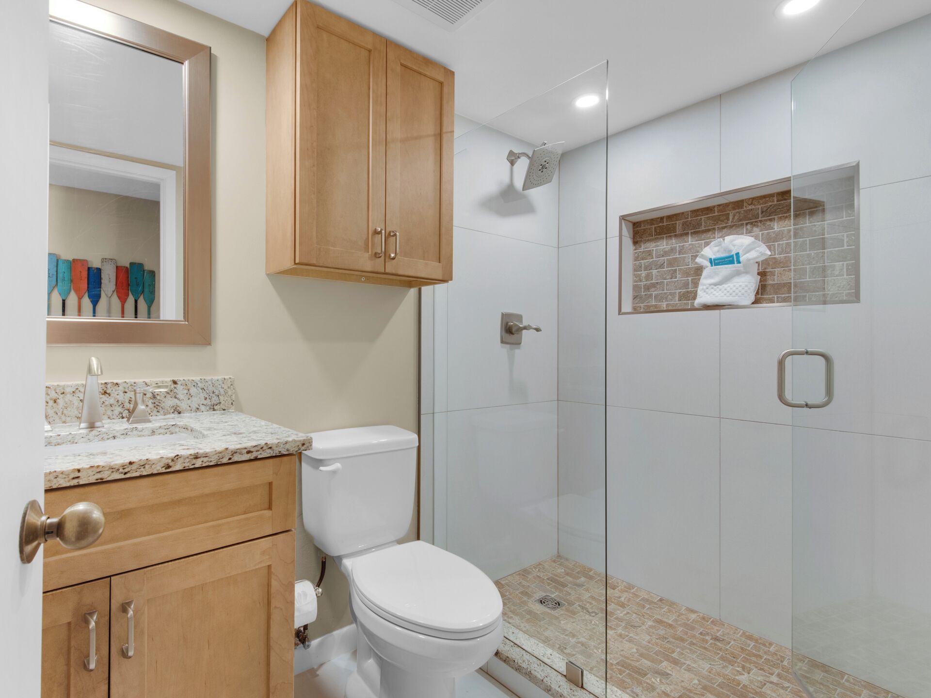 A bathroom with a toilet, a shower, and a vanity with a mirror.