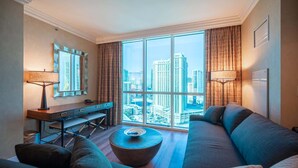 A modern hotel room with a large window offering a city view, a sofa, a desk, and a lamp. - No Resort Fee Strip View Suite + Free Valet + Pool (Las Vegas)