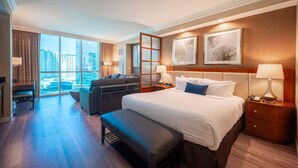 A hotel room with a large bed, a seating area, a desk, and a view of the city. - No Resort Fee Strip View Suite + Free Valet + Pool (Las Vegas)