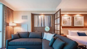 A modern hotel room with a sectional sofa, a round coffee table, a bed, and artwork on the walls. - No Resort Fee Strip View Suite + Free Valet + Pool (Las Vegas)