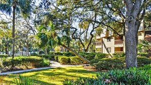 A well-maintained garden with a pathway leading to a building with balconies. - Steps to Beach, Coligny Plaza: Hilton Head Condo! (Hilton Head Island)