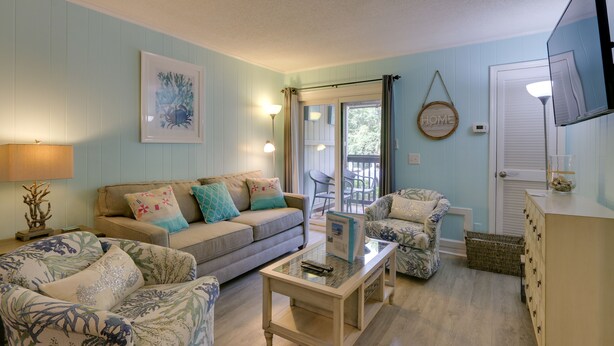 A living room with a sofa, armchairs, a coffee table, and a television. - Steps to Beach, Coligny Plaza: Hilton Head Condo! (Hilton Head Island)