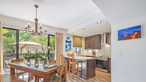 Una cocina moderna con una isla central, electrodomésticos de acero inoxidable y un amplio ventanal con vistas a la vegetación.
