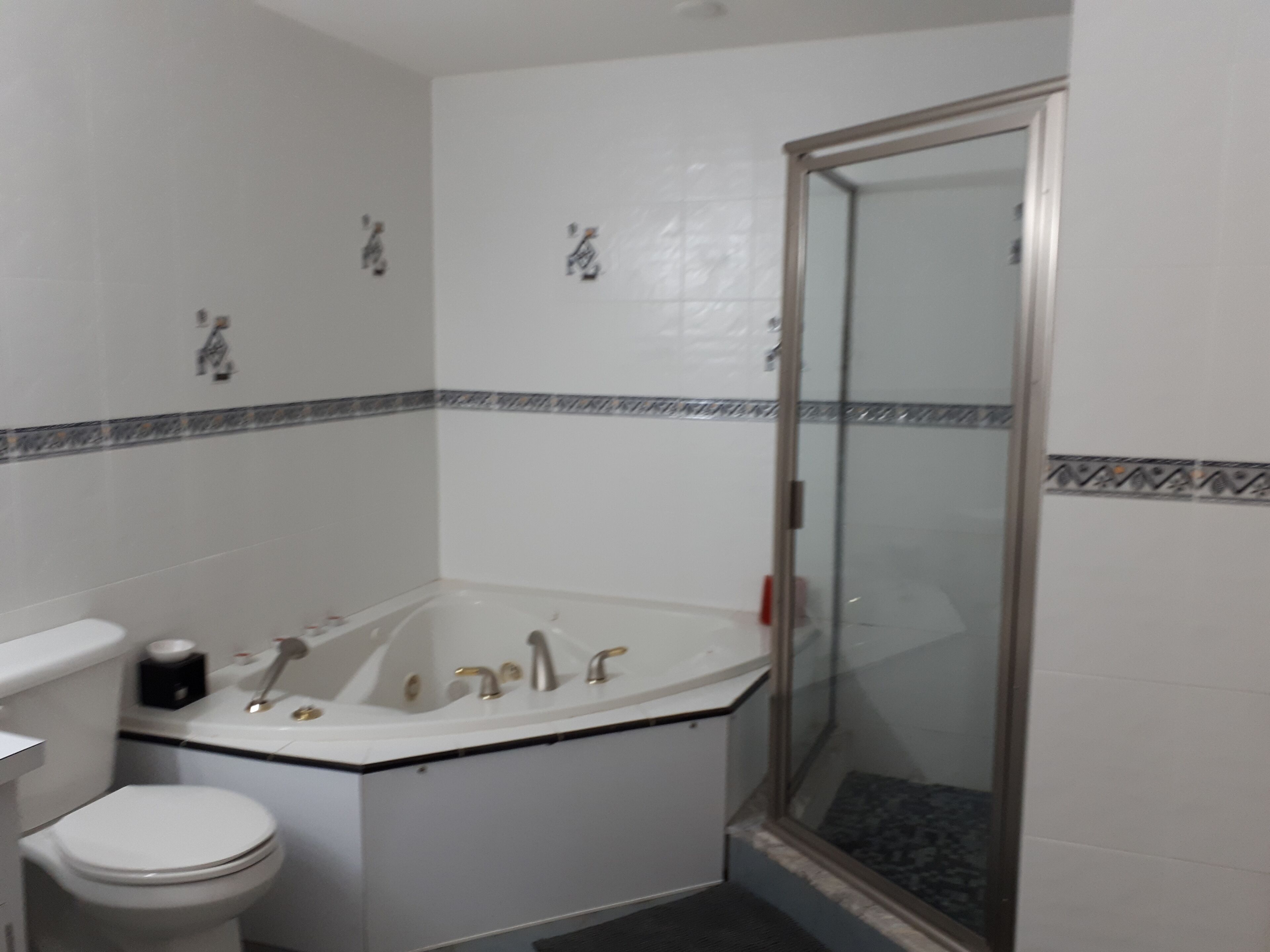 Ein Badezimmer mit einer weißen Badewanne, einer Toilette und einer Duschkabine aus Glas.