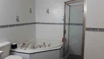 Ein Badezimmer mit einer weißen Badewanne, einer Toilette und einer Duschkabine aus Glas.