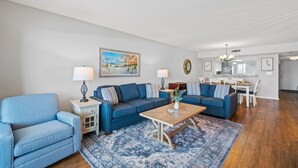 Un salon avec un canapé bleu, une table basse et un tapis à motifs.