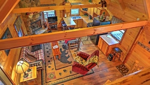 A spacious cabin interior with a loft bedroom, a dining area, and a cozy living room. - Rustic Dundee Log Cabin w/ Hot Tub & Forest Views! (Dundee)