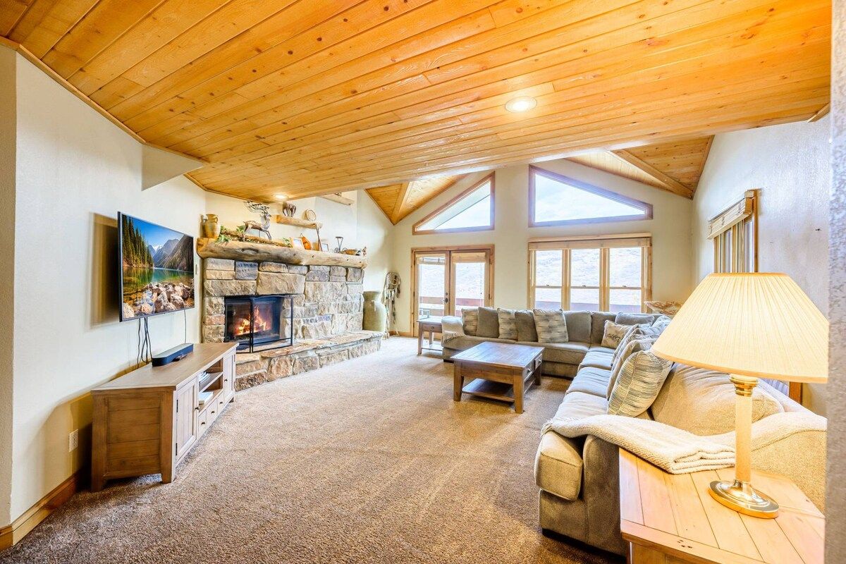 A cozy living room with a stone fireplace, a large window, and a comfortable sofa.