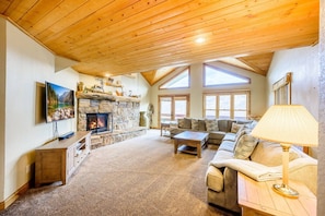 A cozy living room with a stone fireplace, a large window, and a comfortable sofa.