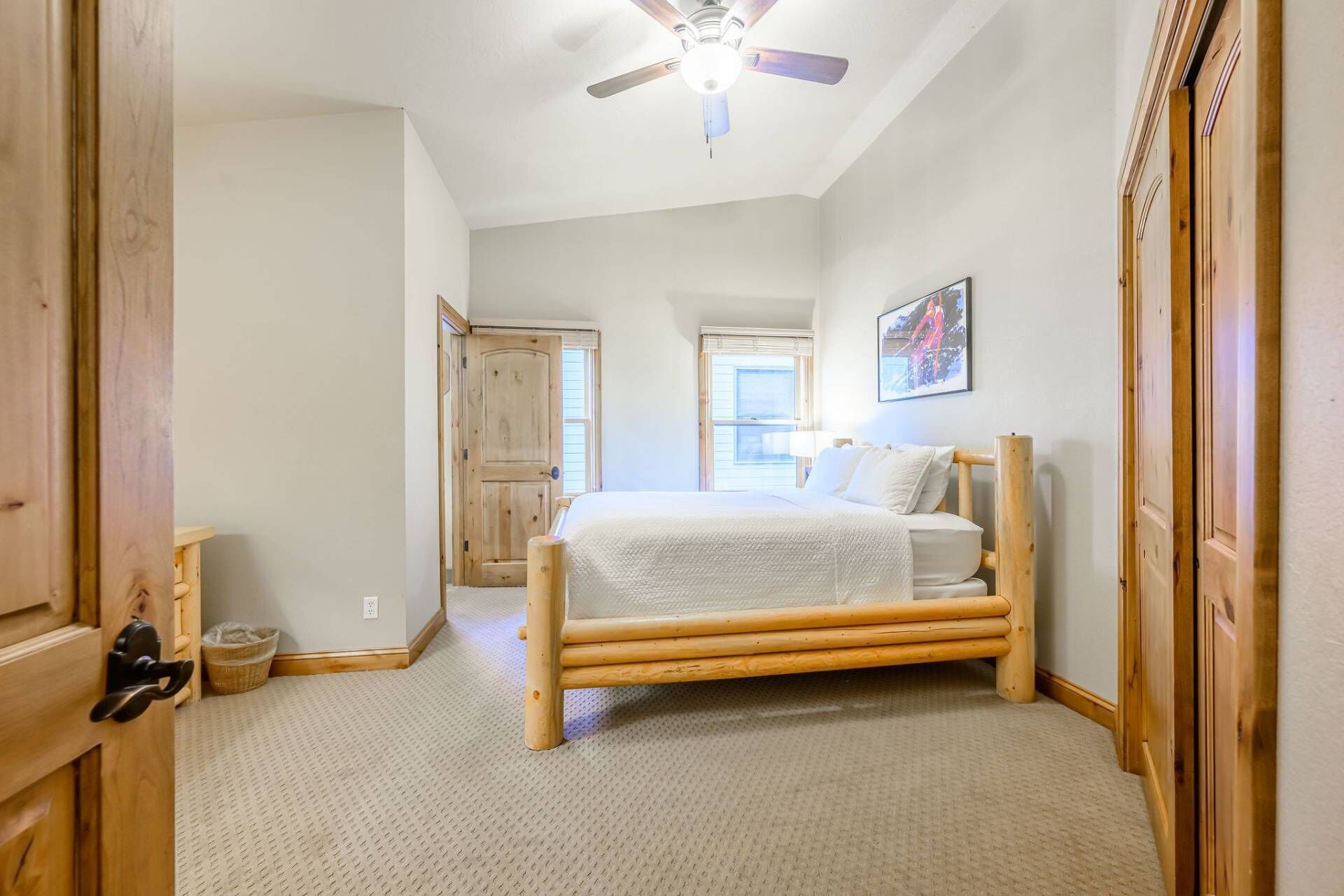 Una camera da letto con un letto di legno, una ventola a soffitto e una finestra con persiane.