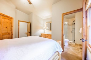 A bedroom with a large bed, wooden wardrobe, a mirror, and a bathroom with a shower and toilet. - Lowell 1175 (Park City)