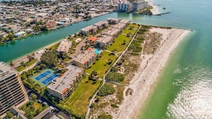 Vista aérea de una zona residencial costera con un puerto deportivo, cancha de tenis y una playa.