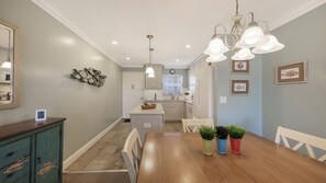 A dining area with a wooden table, chairs, a chandelier, and a kitchen in the background. - Condo #311 Extraordinary Siesta Key Beach View at La Siesta- fully renovated!,**20% off July,Aug,Sept,Oct Reservations (Sarasota)