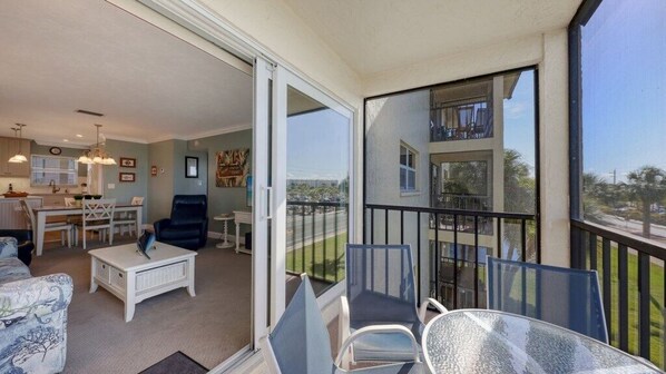 A balcony with a view of a building, a dining area with a table and chairs, and a living area with a sofa and a coffee table. - Condo #311 Extraordinary Siesta Key Beach View at La Siesta- fully renovated!,**20% off July,Aug,Sept,Oct Reservations (Sarasota)