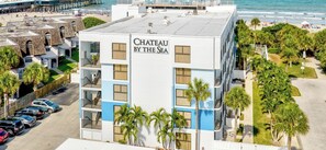 A multi-story hotel named 'Chateau by the Sea' with balconies, parking, and a view of the beach.