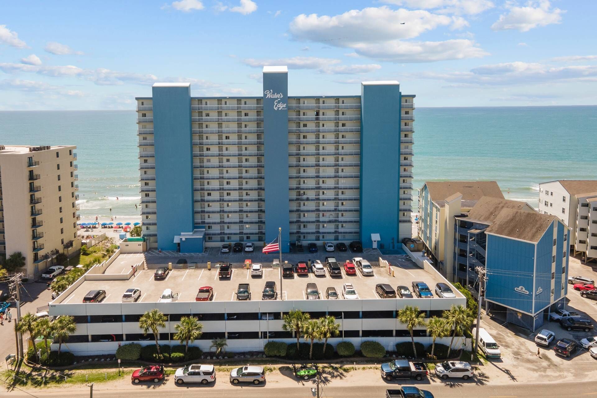 A hotel with a parking garage and a view of the beach.