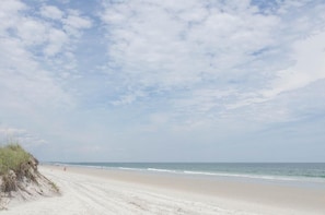 Uma praia com céu claro e ondas suaves.