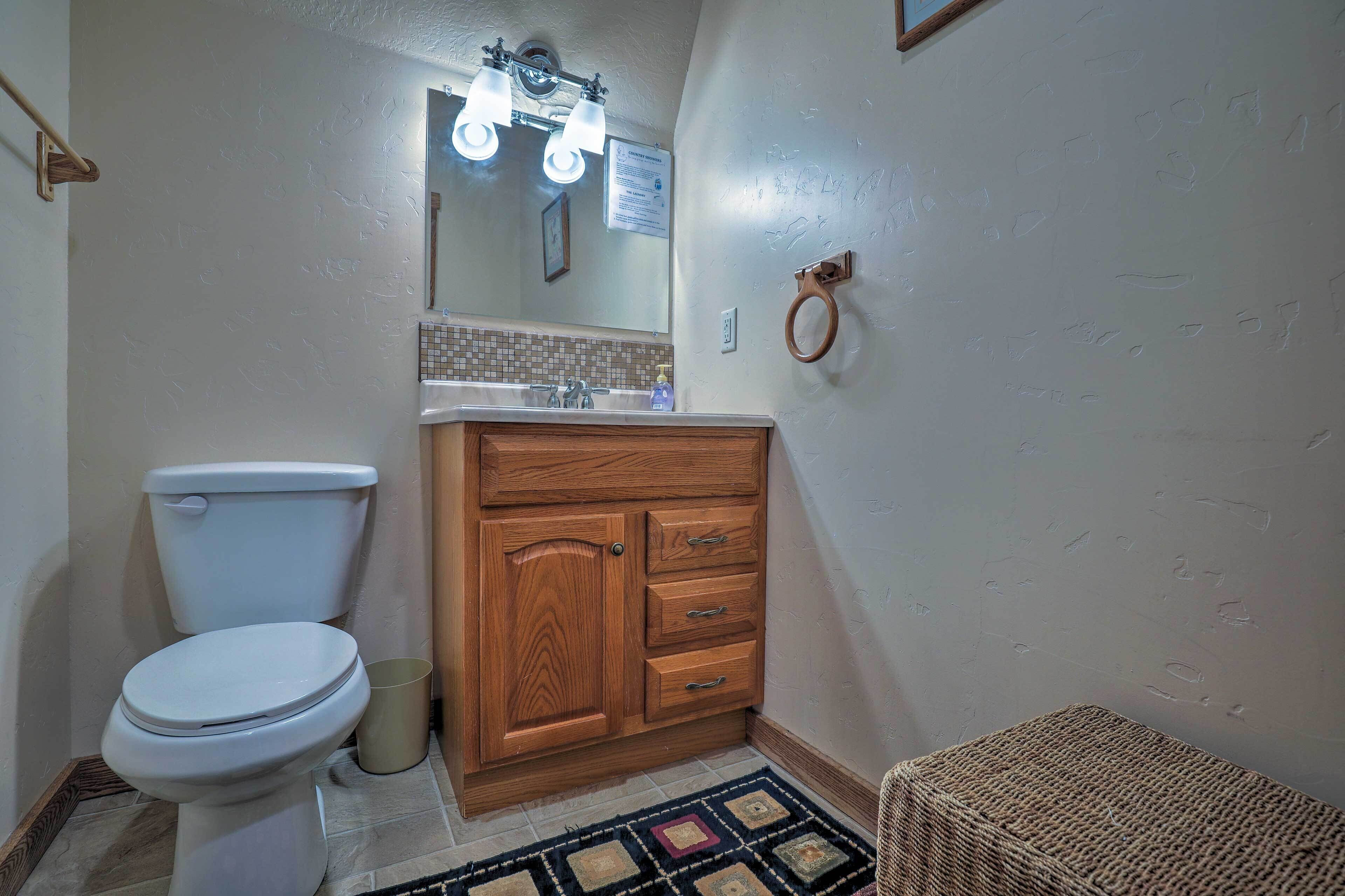 Un baño con inodoro, mueble de madera y lavamanos.