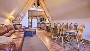 Ein gemütliches Wohnzimmer mit einer Ledersofa, einem Esstisch mit Holzsesseln und einer Küche im Hintergrund.