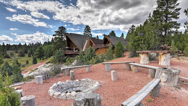 Eine Lodge mit einem Steinkamin und Holzbanken, umgeben von einem bewaldeten Gebiet.