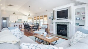 Un salón amplio con chimenea, un comedor y una cocina con armarios blancos.