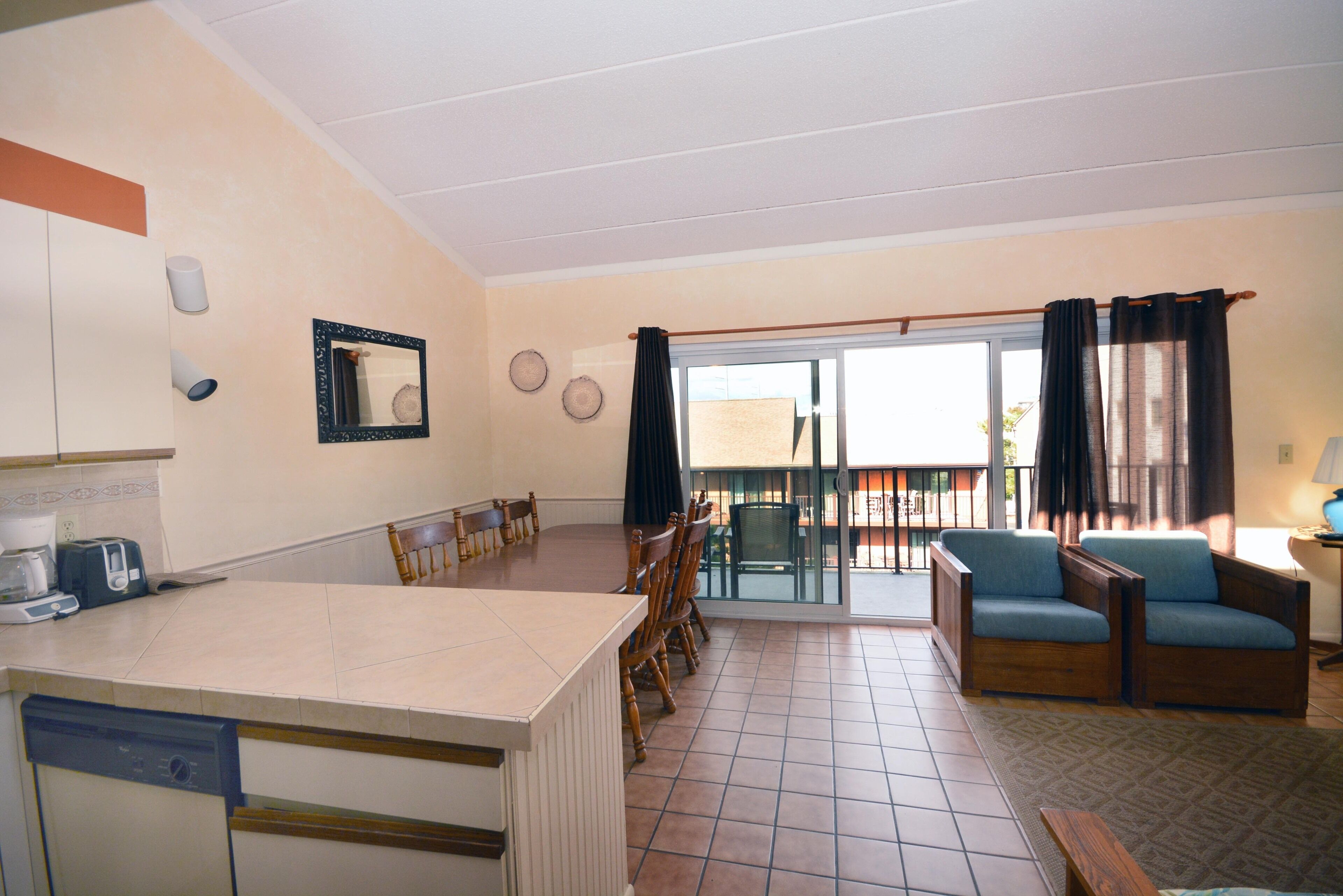 A spacious kitchen with a dining area, a built-in dishwasher, and a large window overlooking a balcony.