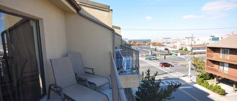 Ein Balkon mit zwei Stühlen, Blick auf eine Straße mit Autos und Gebäuden, und ein klarer Himmel.
