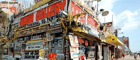 Un escaparate colorido con varios letreros que anuncian ventas de arte y galerías.