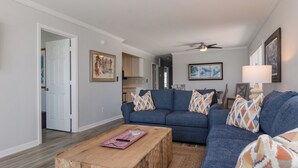 A living room with a blue sofa set, a wooden coffee table, and a ceiling fan.