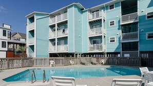 A swimming pool with white lounge chairs, surrounded by a wooden fence.