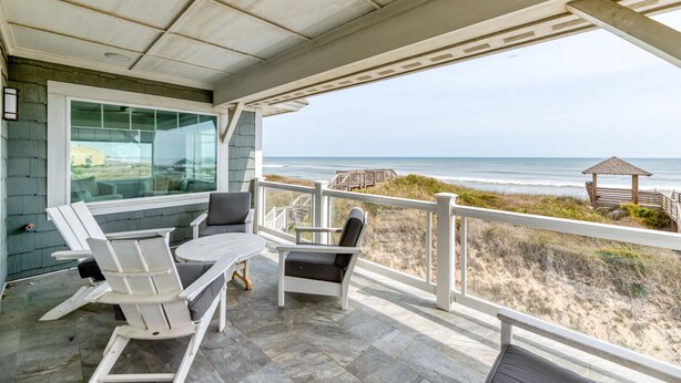 A covered outdoor seating area with a view of the beach and ocean.