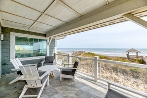 Een overdekt terras met uitzicht op het strand en de oceaan.