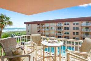 Ein Balkon mit Korbmöbeln, einem Pool und Meerblick.