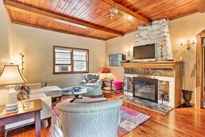 Un salón acogedor con chimenea, techo de madera y asientos cómodos.