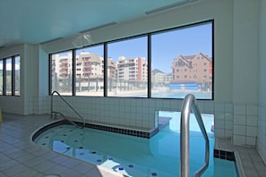 Una piscina interior con vistas despejadas a edificios a través de amplios ventanales.