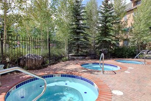 A pool area with multiple hot tubs and a brick pathway.