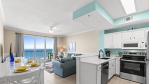 A modern kitchen with white cabinets, a built-in oven, and a dining area with a table set for two.