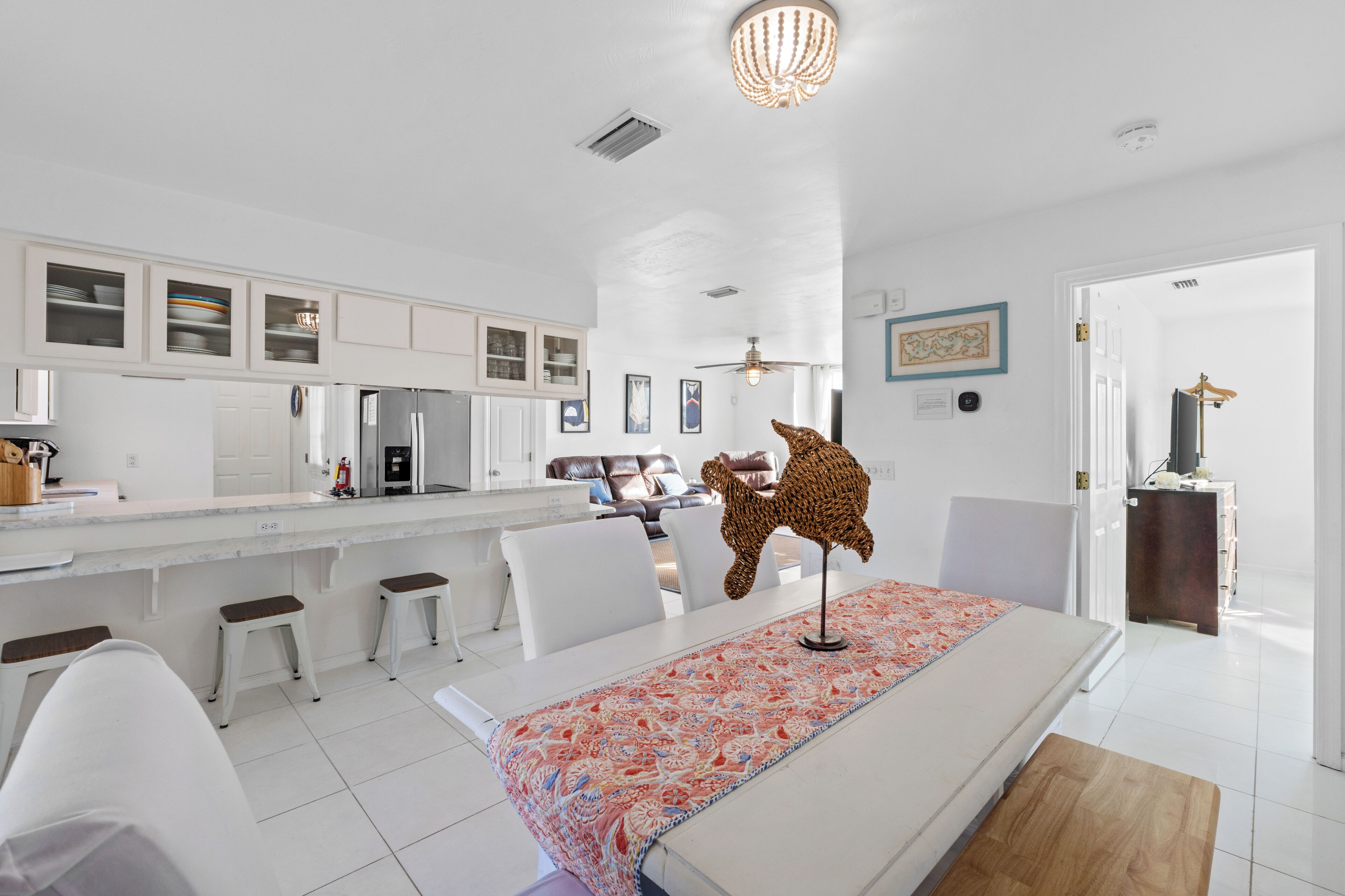 A modern kitchen with white cabinetry, a central island, and a dining area with a table and chairs.