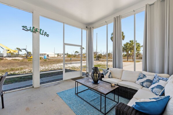 A spacious room with large windows, a white sofa, a coffee table, and a view of a construction site.