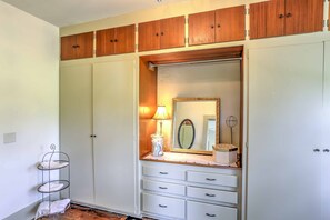 A room with a large wardrobe, a mirror, and a small shelf with a lamp. - Historic Ottawa Lake House: Deck, Barn + 96 Acres! (Ottawa Lake)