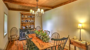 A dining area with a wooden table, chairs, a chandelier, and a china cabinet. - Historic Ottawa Lake House: Deck, Barn + 96 Acres! (Ottawa Lake)