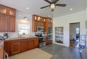 A modern kitchen with wooden cabinets, stainless steel appliances, and a ceiling fan. - Historic Ottawa Lake House: Deck, Barn + 96 Acres! (Ottawa Lake)