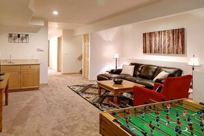 A living room with a sofa, coffee table, and a foosball table.