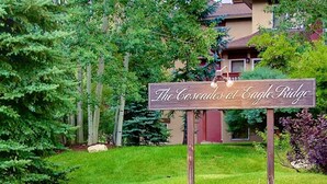 Un letrero que dice "The Cascades at Eagle Ridge" con un fondo de vegetación exuberante y un edificio de techo marrón.