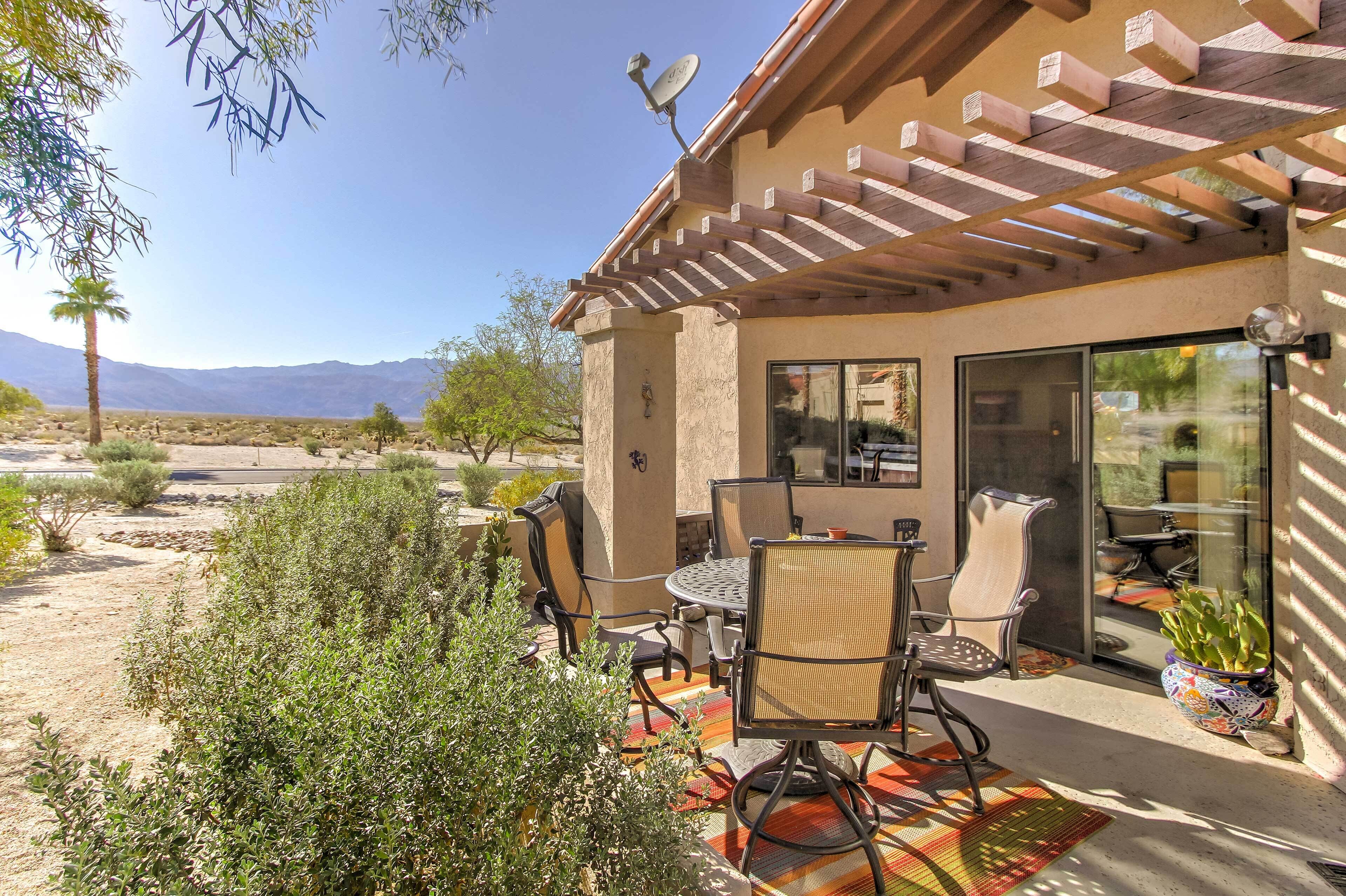 Un patio con mobiliario exterior, una pérgola y vistas a las montañas.
