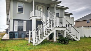 Ein zweistöckiges Haus mit weißer Fassade, einer Veranda und einer Treppe, die zum zweiten Stock führt.